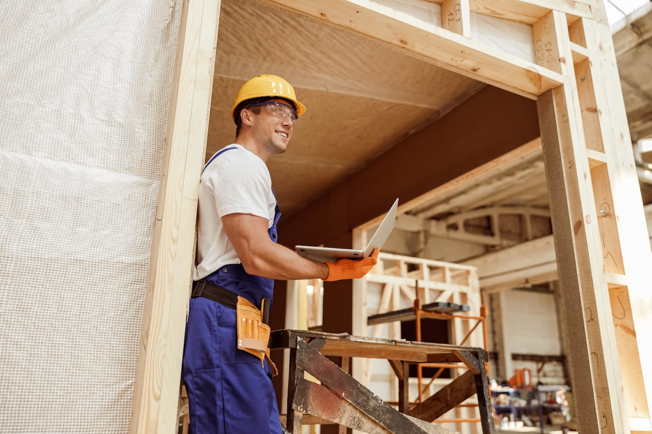 Joyful male builder using laptop at construction site