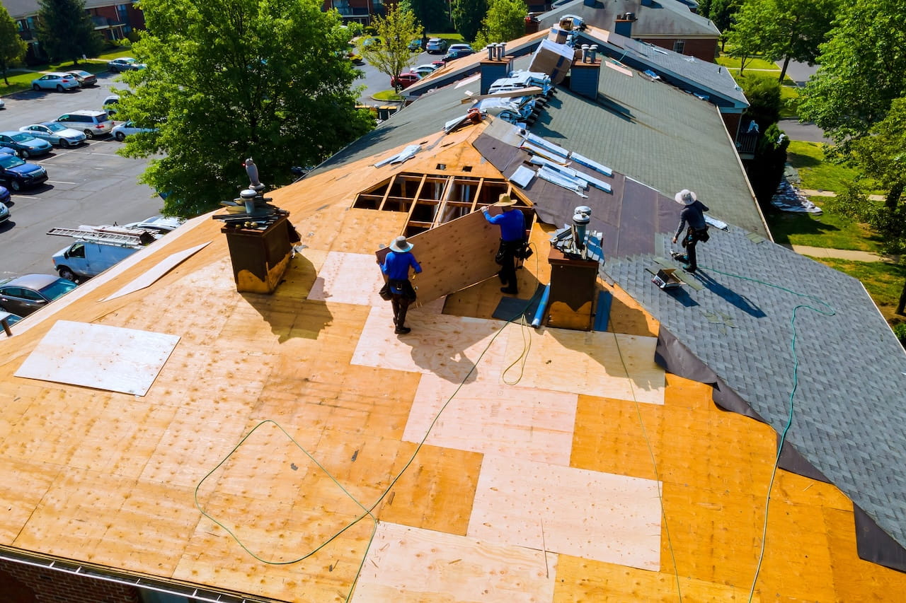 Roofers replacing old asphalt bitumen shingles on house roof in order to repair roof
