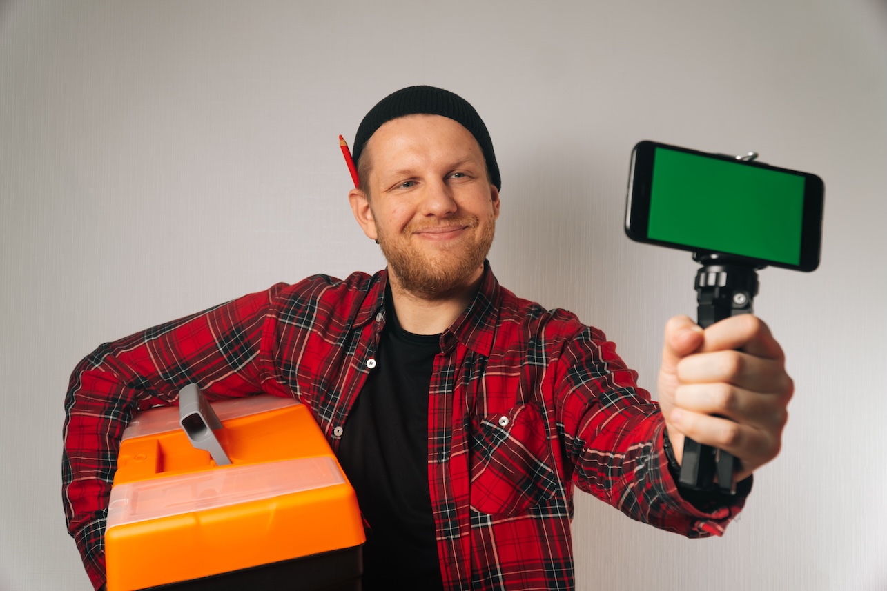 A builder is a man of Caucasian portrait as taking a selfie on a smartphone. The concept of plumbing photography for the google business verification
