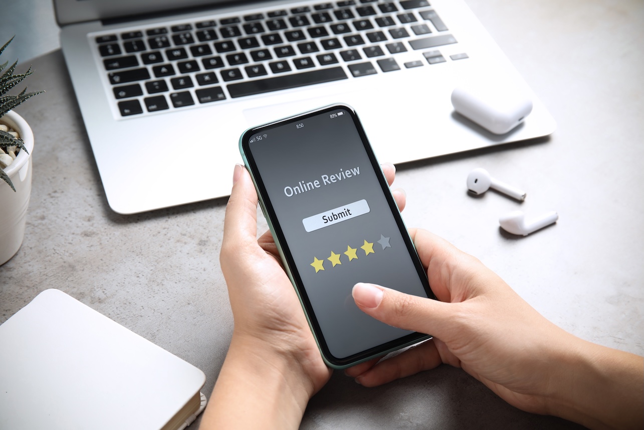 Woman using smartphone to give feedback at table, closeup. Customer review
