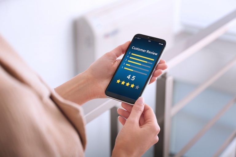 Woman using smartphone to give feedback indoors, closeup. Google review response